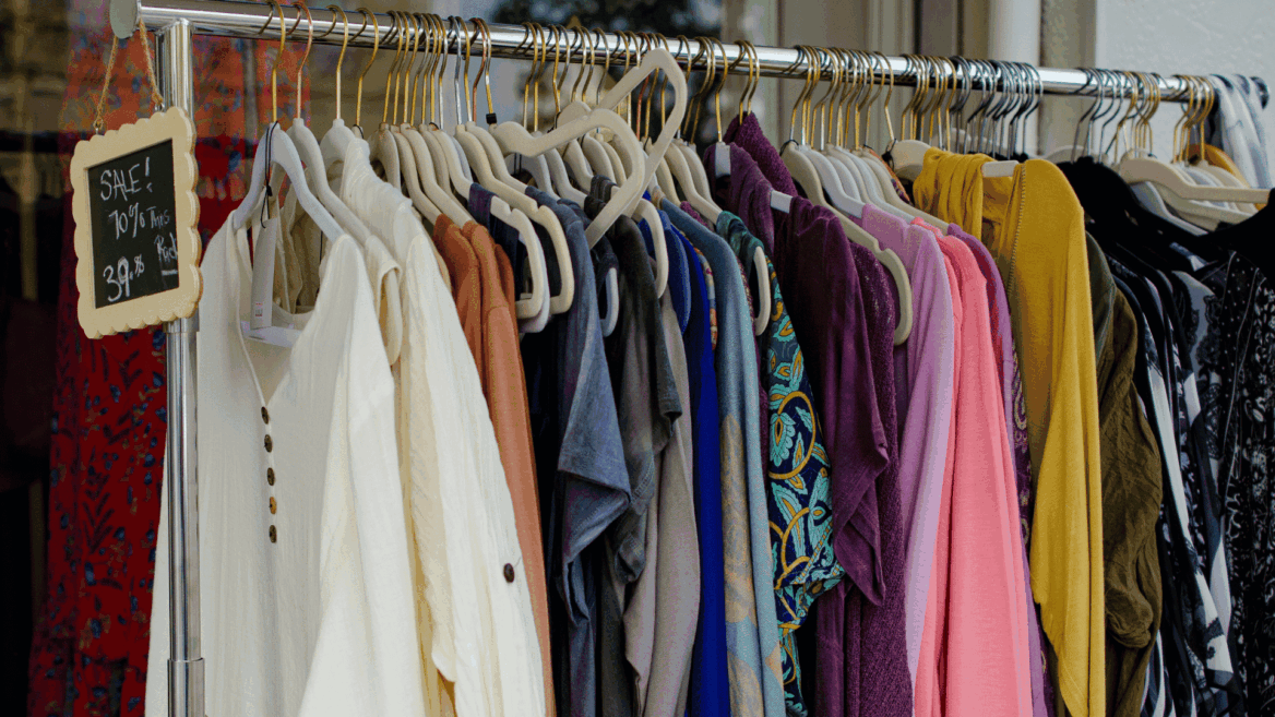 colorful boutique clothing rack with sale sign