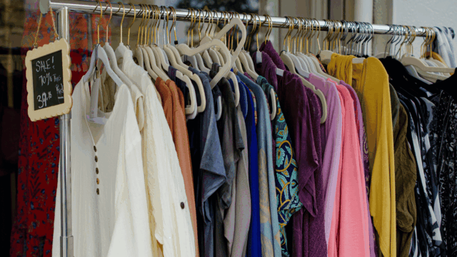 colorful boutique clothing rack with sale sign