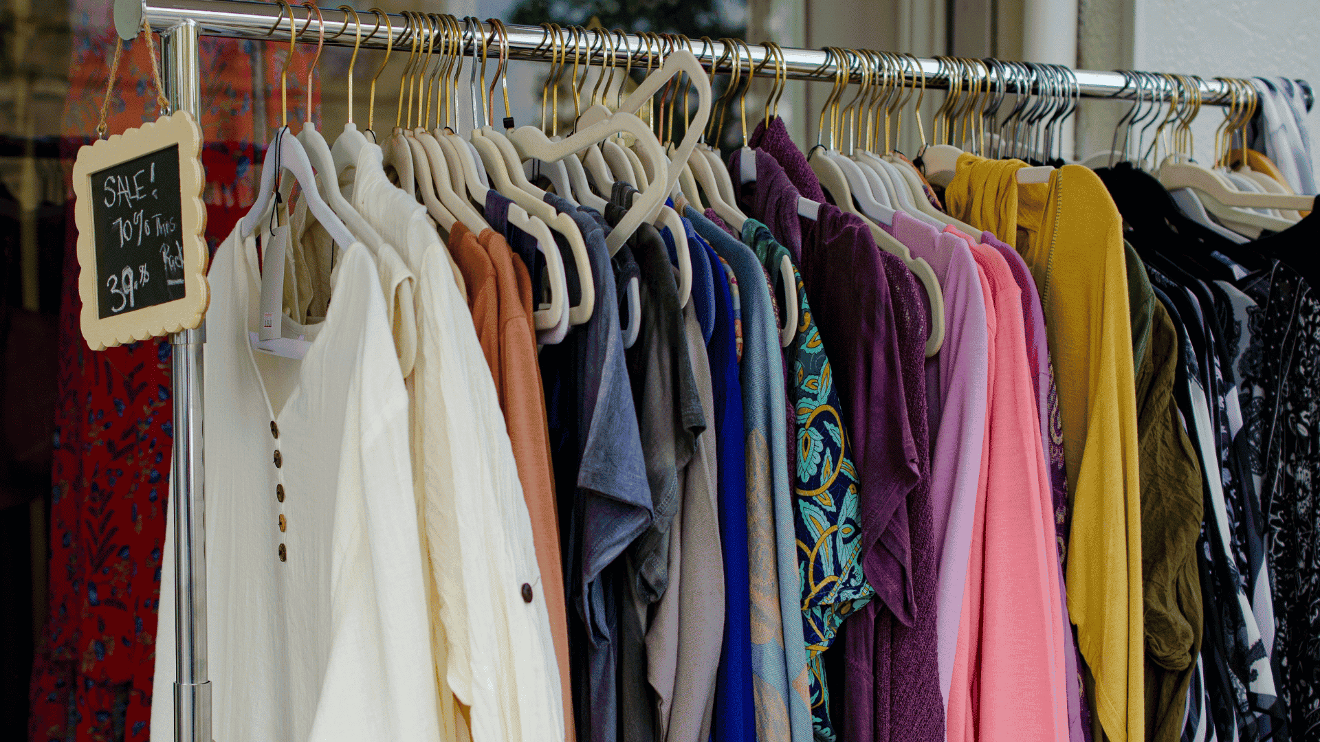 colorful boutique clothing rack with sale sign