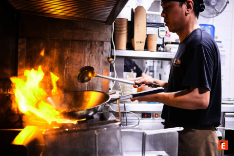 cocinero de restaurante con wok en llamas