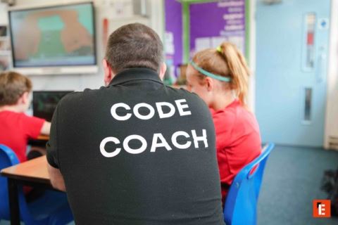 coding coach mentoring students in a tech classroom