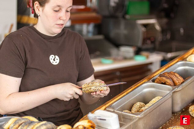 employé coupe un bagel aux graines en boulangerie