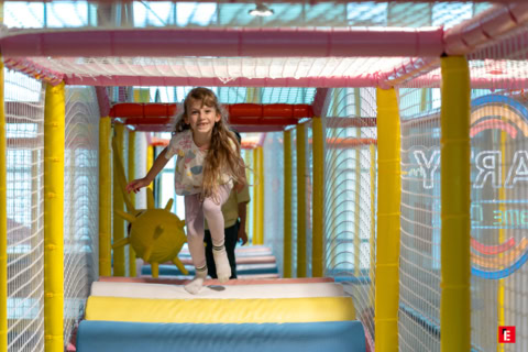 enfant souriante dans tunnel de jeu intérieur coloré