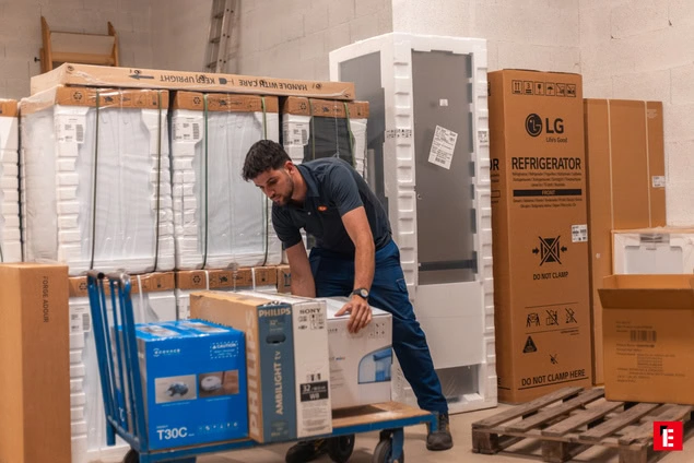 employé manutentionne réfrigérateurs et cartons en entrepôt