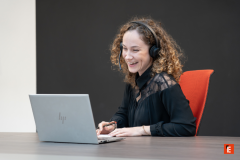 femme souriante en télétravail avec casque et ordinateur