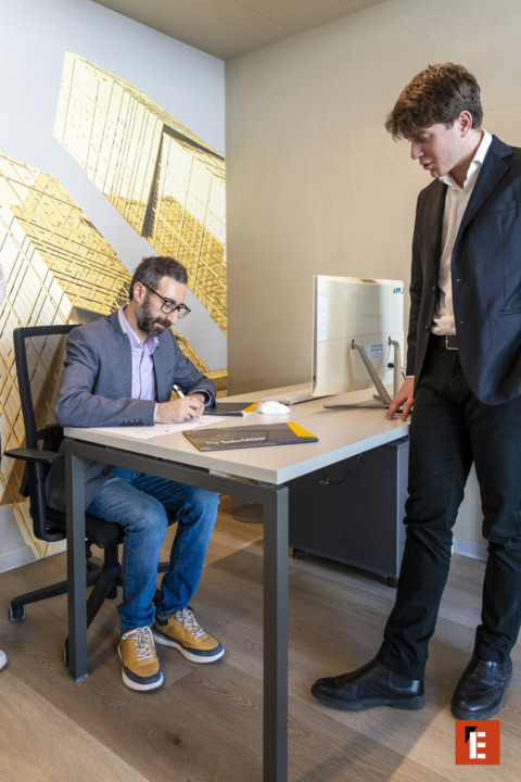 firma in ufficio moderno con collega e scarpe gialle