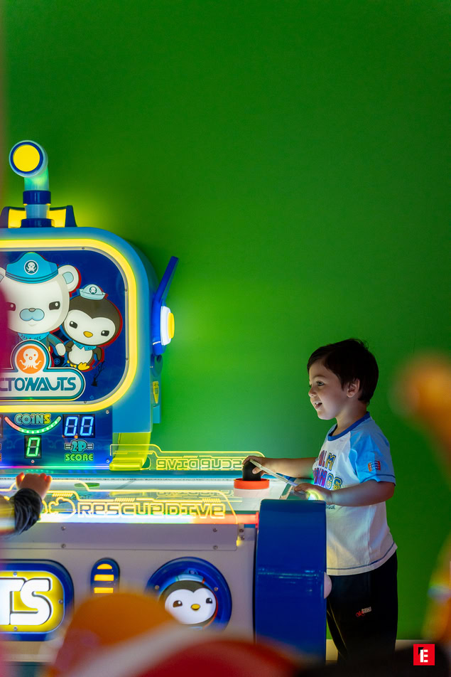 garçon jouant à une machine darcade lumineuse