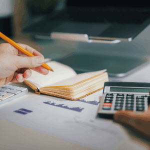 hand of a man calculating things and writing on a little notebook