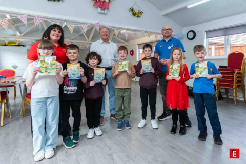 children proudly displaying booklets in community room