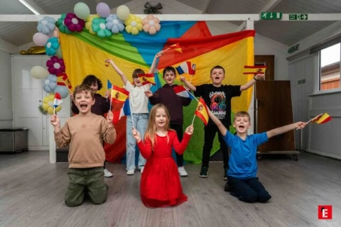 children cheering with spanish flags in colorful hall