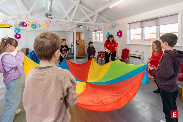 children playing parachute game in community hall