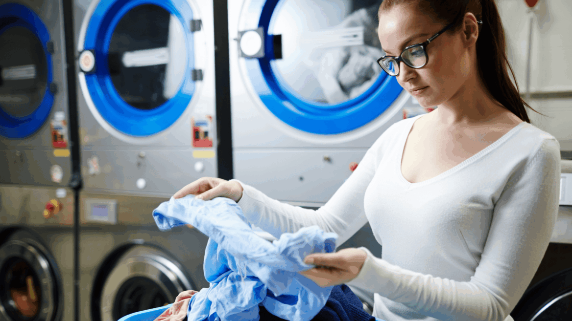 mujer revisando ropa azul en lavandería industrial