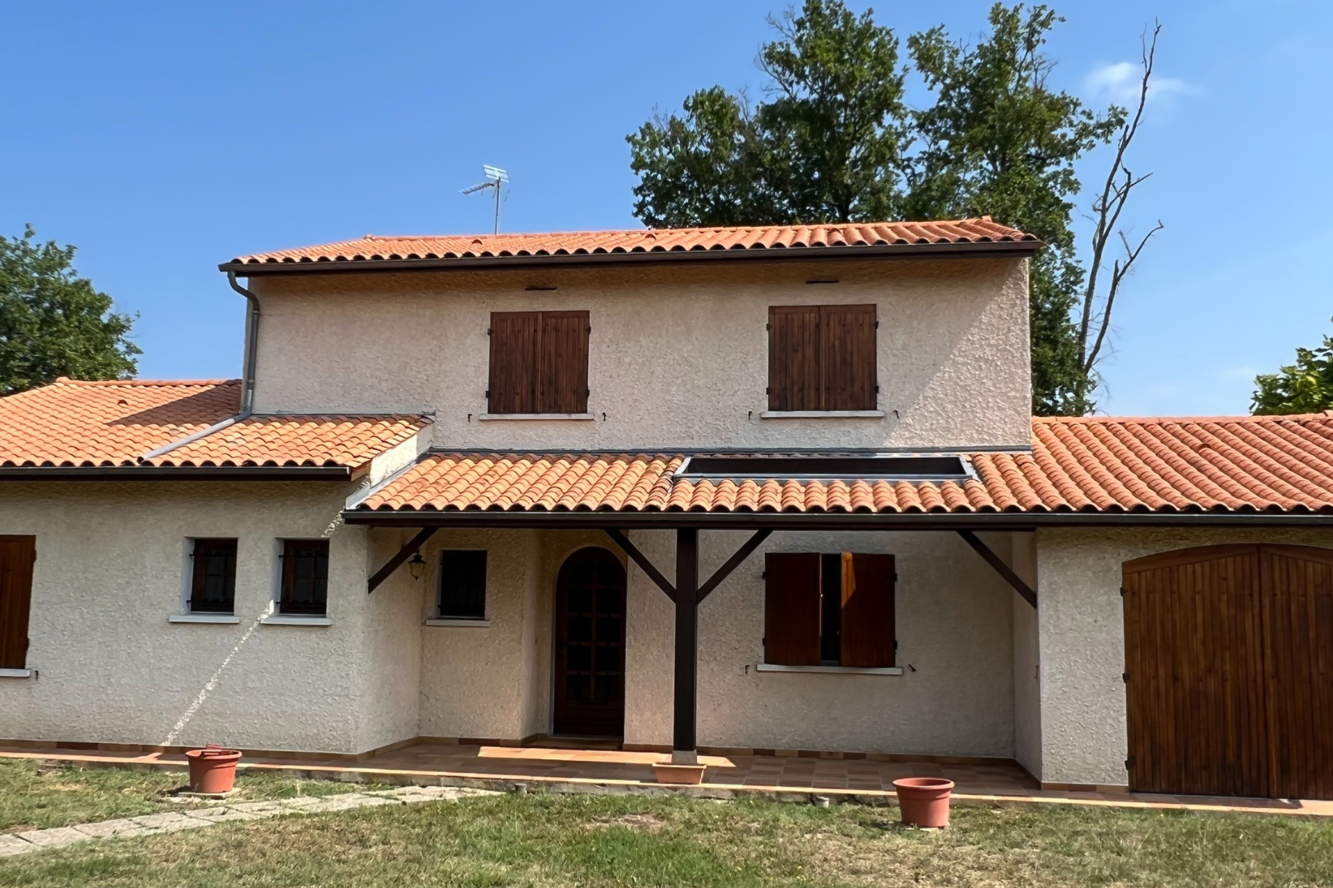maison à toit tuiles terracotta et porche en bois