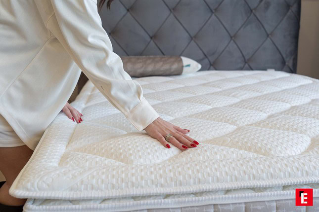 mano con unghie rosse su topper trapuntato