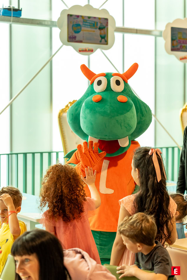 mascotte verte tape dans la main des enfants