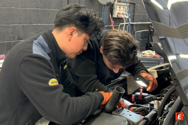 meccanici in officina: ispezione motore con torcia