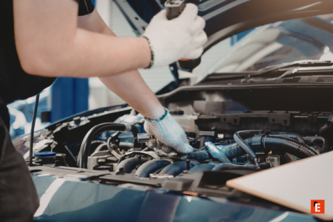 meccanico con guanti ispeziona motore in officina