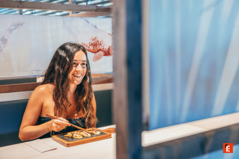 mujer sonriente disfruta gyozas en restaurante japonés