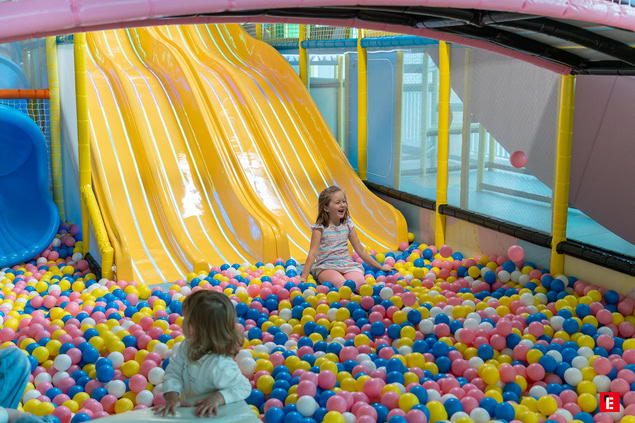 enfants rieurs dans piscine à balles et toboggan jaune