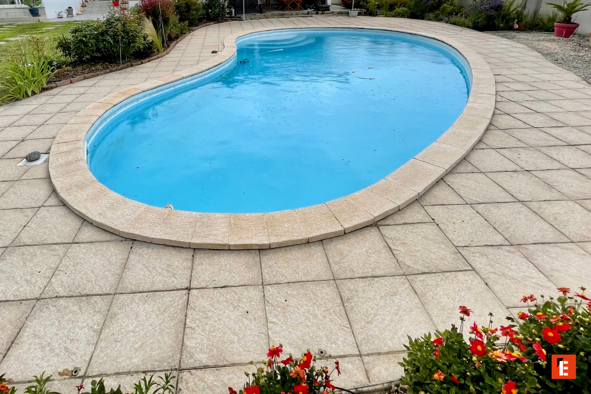 piscine en haricot bleue, terrasse et jardin fleuri