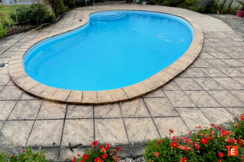 piscine turquoise en forme de rein sur terrasse dallée