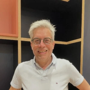 portrait dhomme souriant en polo blanc et lunettes rondes