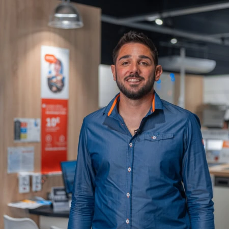 vendeur souriant devant téléviseurs en magasin