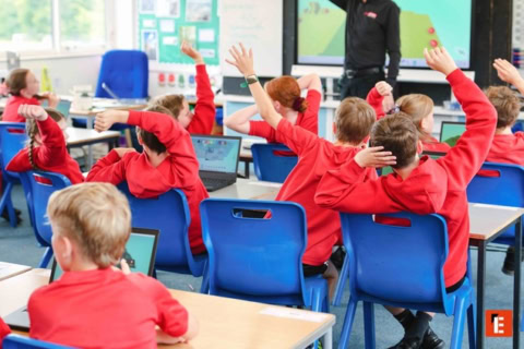 primary classroom: pupils raising hands with laptops