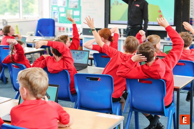 primary classroom: pupils raising hands with laptops