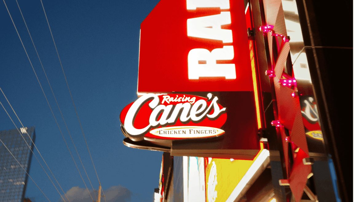 raising canes illuminated storefront sign at dusk