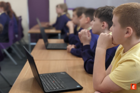 students focused on laptops in classroom row