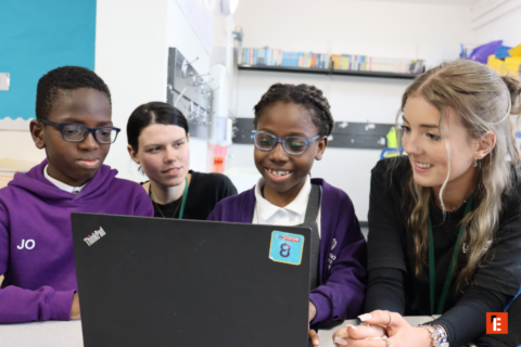 students and teachers collaborating around a laptop