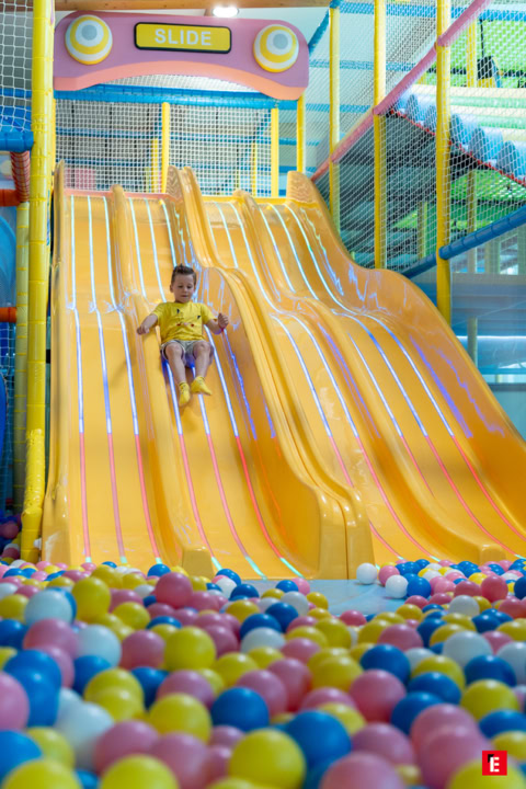 enfant sur toboggan jaune dans piscine À balles