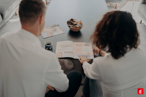 deux personnes lisent un magazine ensemble à table