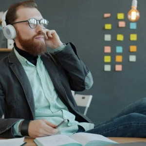 uomo creativo in ufficio con cuffie e taccuino