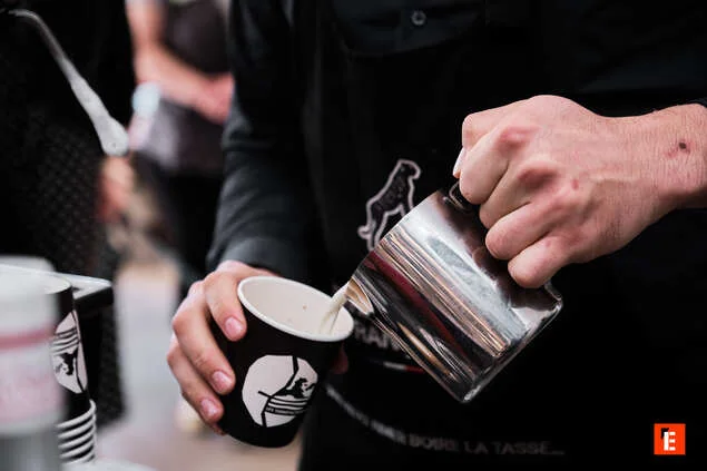 barista versant du lait dans un gobelet de café