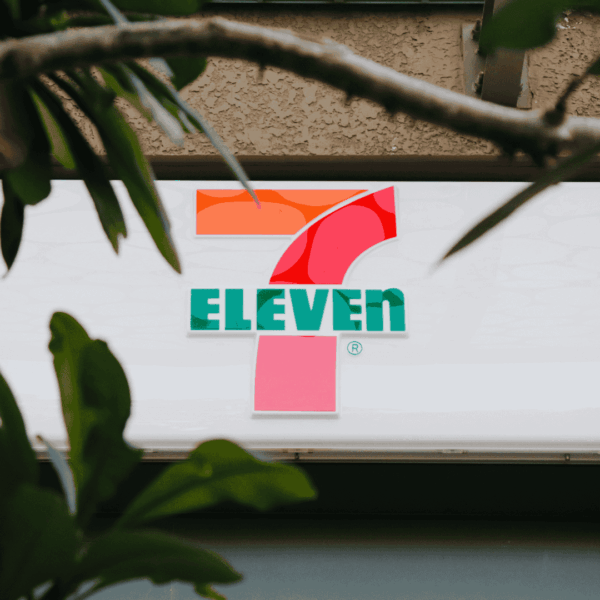 7 eleven sign framed by blurred green leaves