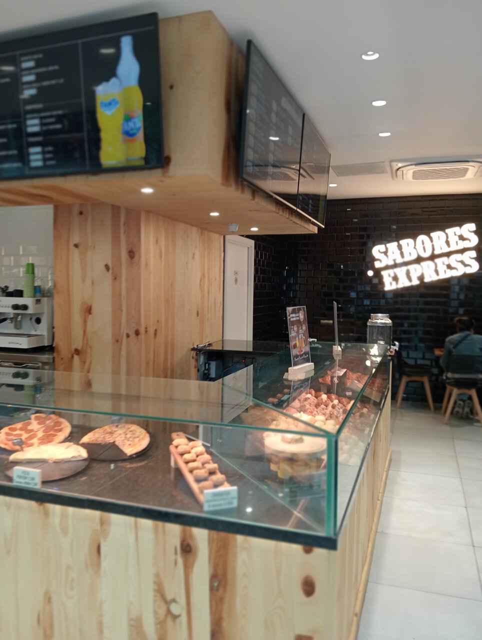 cafetería moderna con vitrina de pasteles y pizzas