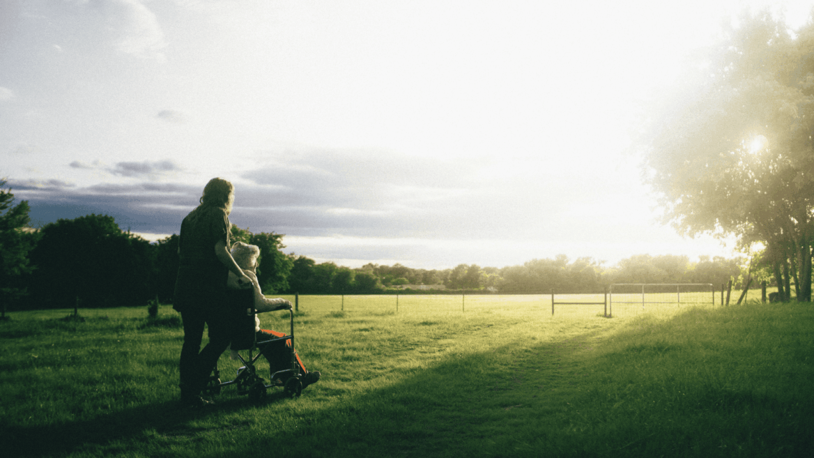 caregiver pushing wheelchair at golden hour