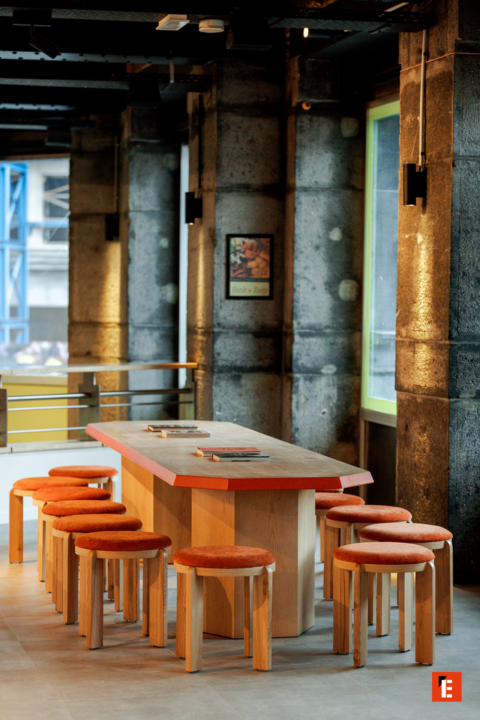 espace commun industriel : table bois et tabourets orange