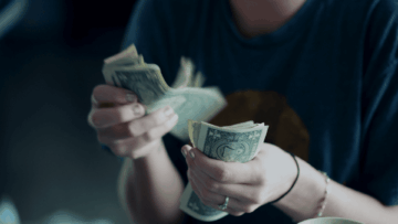 close up of hands counting us one dollar bills
