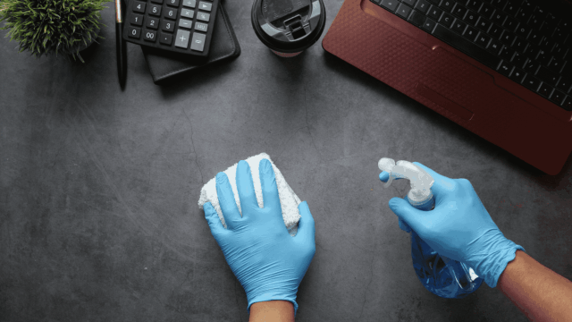 workspace desk cleaning with gloves and spray