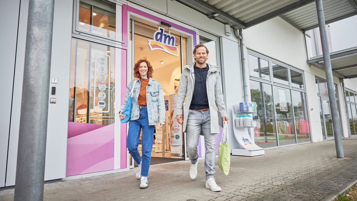 lächelnde kunden verlassen dm mit einkaufstaschen
