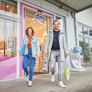 lächelnde kunden verlassen dm mit einkaufstaschen