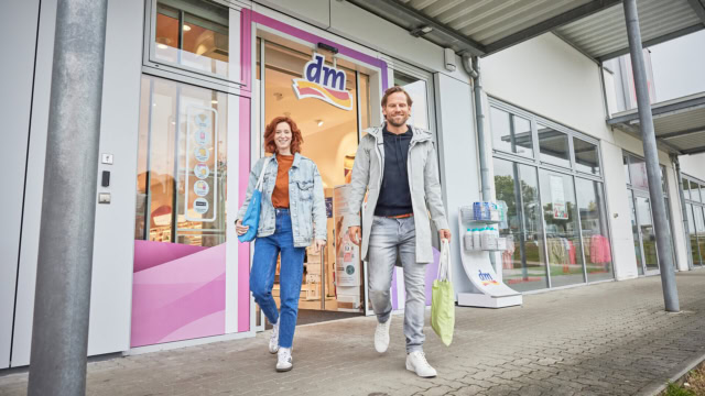 lächelnde kunden verlassen dm mit einkaufstaschen