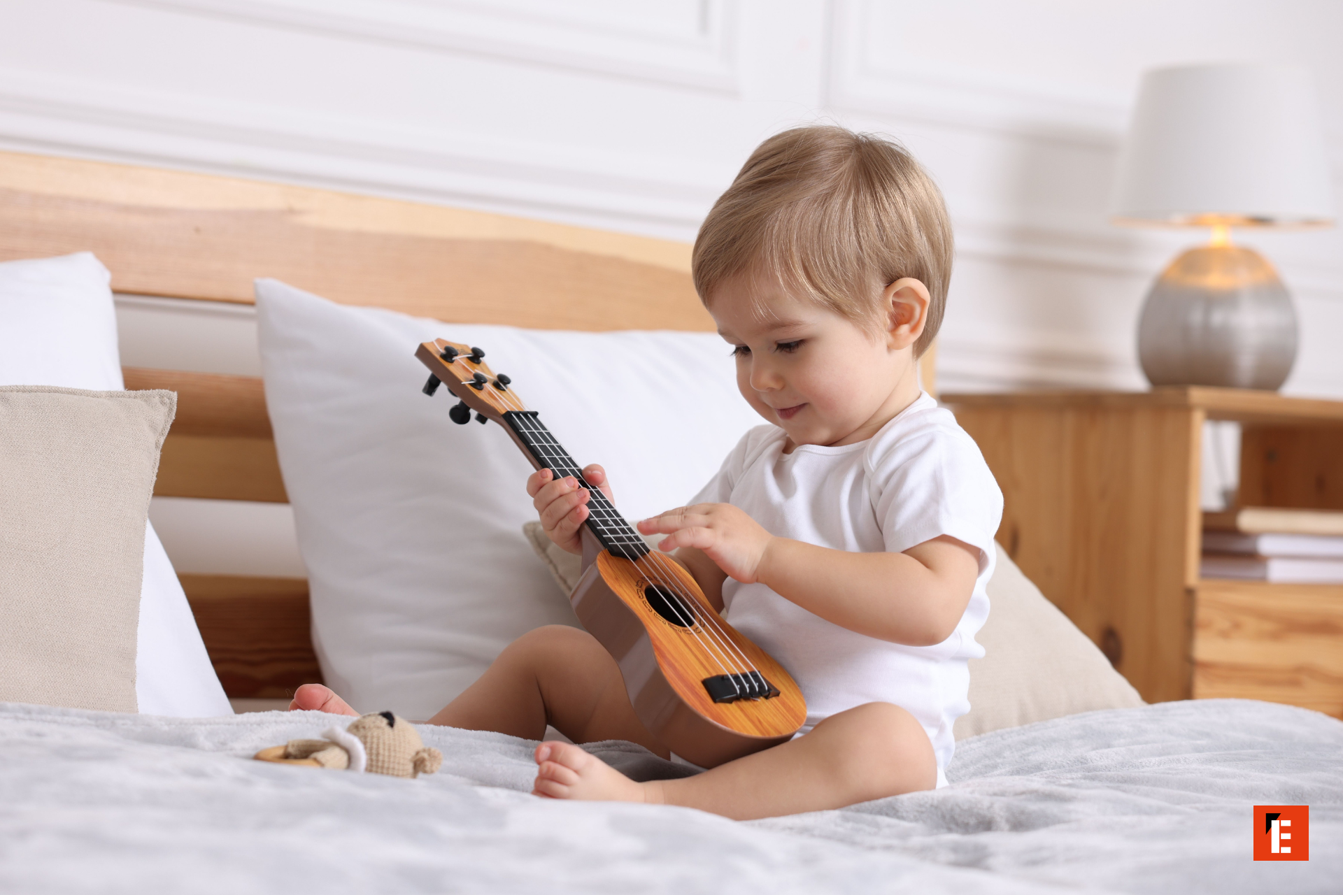 bébé jouant du ukulélé sur lit douillet