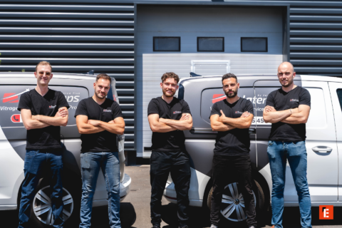 Équipe de techniciens en vitrage devant leurs camionnettes