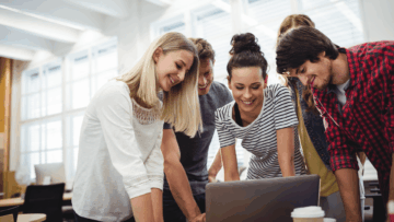 equipo colaborativo en oficina revisando portátil