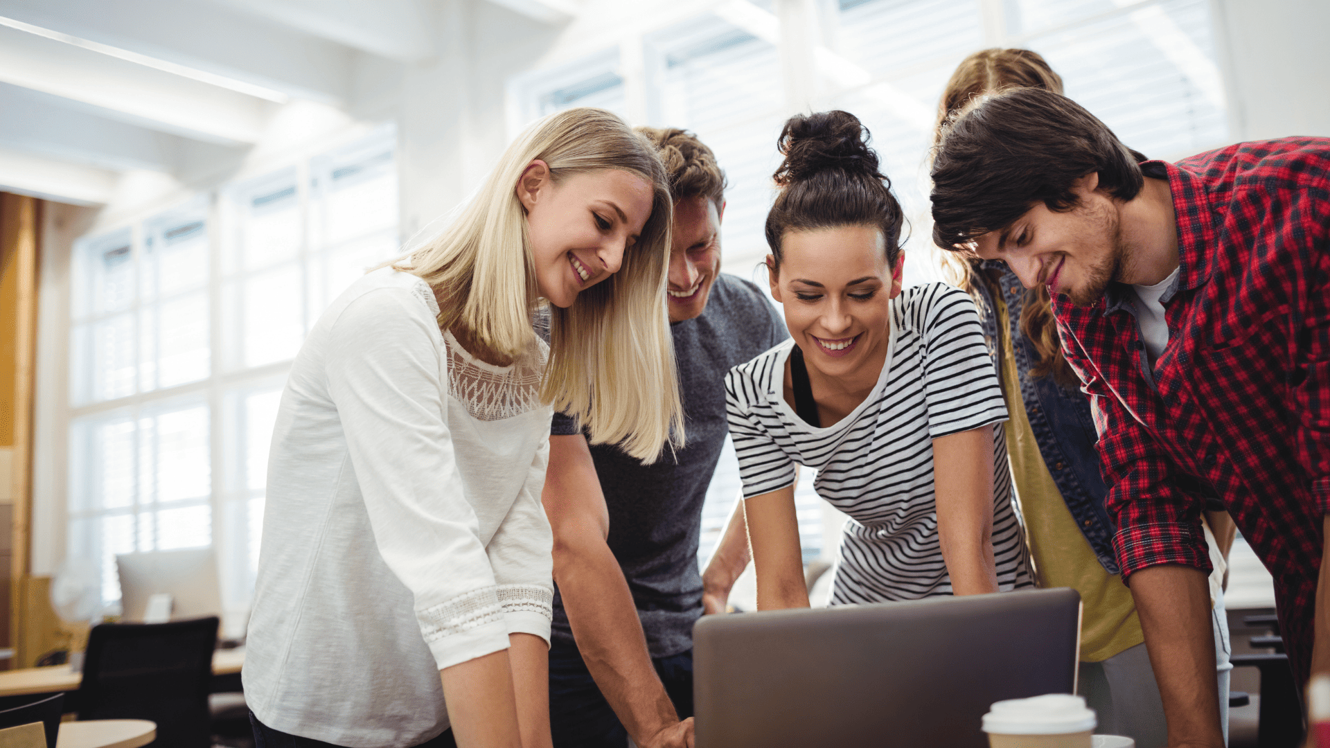 equipo colaborativo en oficina revisando portátil