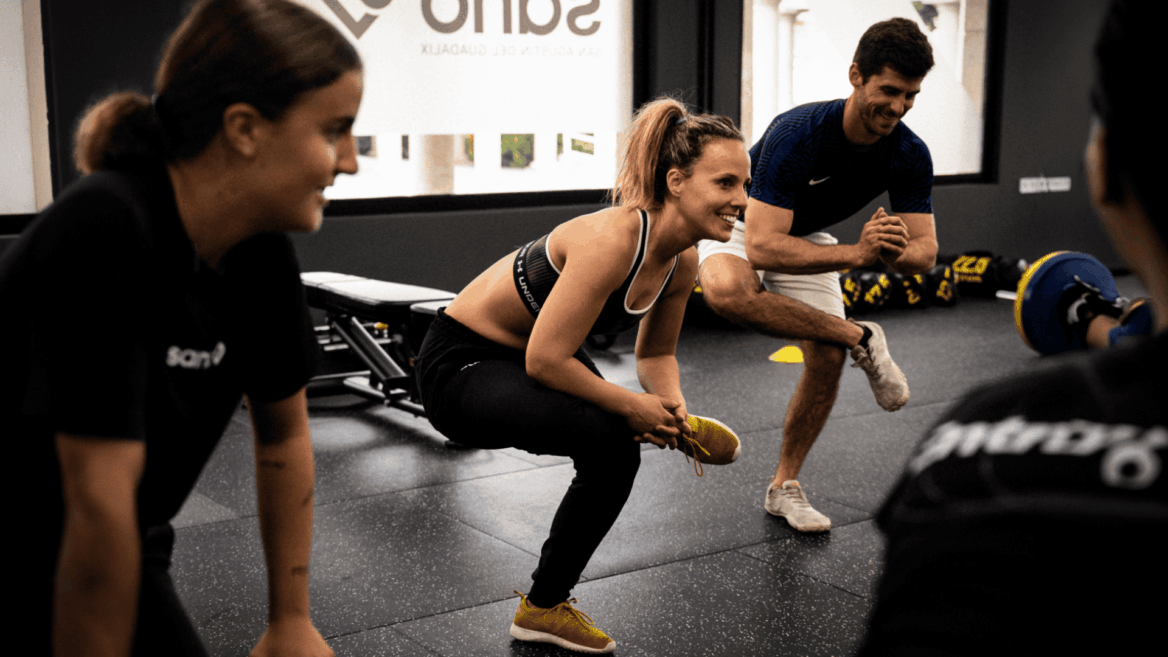 Estiramientos de fitness en grupo con entrenador sonriente.